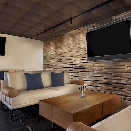 A modern living room with a cream sofa, wooden coffee table, stone accent wall, and a wall-mounted TV.