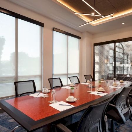 A modern conference room with a long table, office chairs, and large windows for a meeting setup.